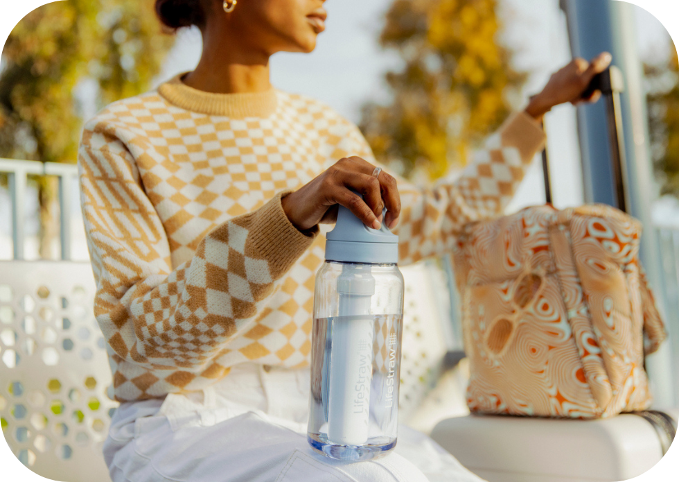 Błękitna butelka LifeStraw w&nbsp;scenerii wakacyjnej